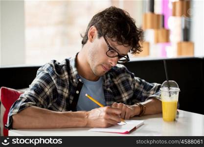 lifestyle, creativity, freelance, inspiration and people concept - creative man with notebook or diary writing and drinking juice at cafe