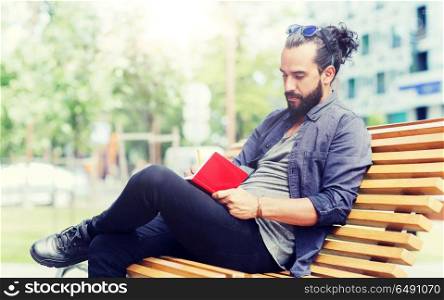 lifestyle, creativity, freelance, inspiration and people concept - creative man with notebook or diary writing sitting on city street bench. man with notebook or diary writing on city street. man with notebook or diary writing on city street