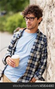 lifestyle, drinks and people concept - man in eyeglasses drinking coffee from disposable paper cup over street wall