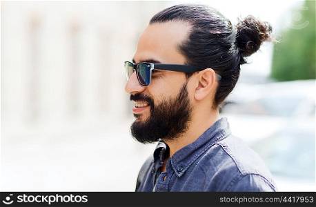 lifestyle, emotion, expression and people concept - happy smiling man with beard and sunglasses on city street