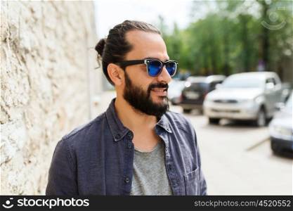 lifestyle, emotion, expression and people concept - happy smiling man with beard and sunglasses on city street