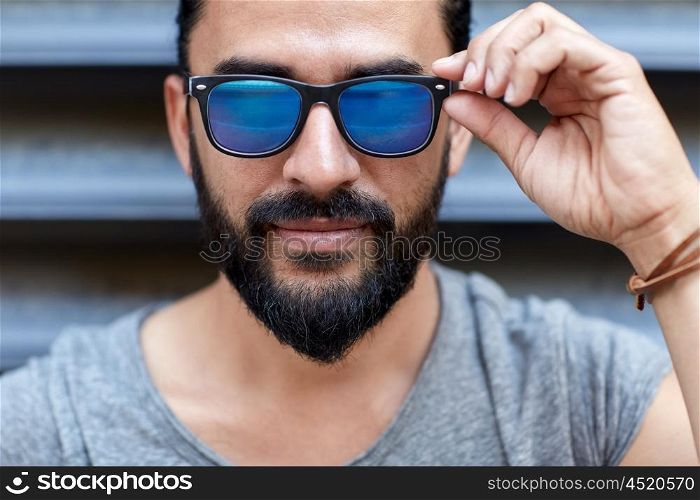 lifestyle, emotion, expression and people concept - happy smiling man with sunglasses and beard on city street