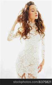 Lifestyle fashion photo of beautiful woman in white lace dress with long curled hair. Lovely bride. Wedding style. Happy woman