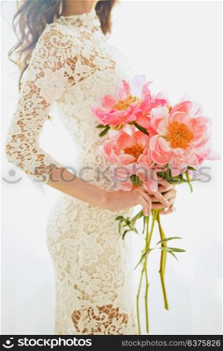 Lifestyle fashion photo of beautiful young woman in white lace dress with pink peony. Holidays and Events. Wedding. Valentine?s Day. Spring blossom. Summer season.
