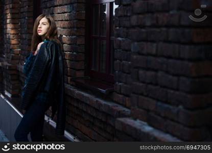 Lifestyle fashion portrait of brunette girl in rock black style, standing outdoors in the city street. Lifestyle fashion portrait of brunette girl in rock black style, standing outdoors in the city street.