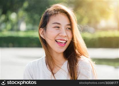 Lifestyle happy young adult asian woman smiling with teeth smile outdoors and walking on city street at sunset time. Sensual smile, stunning face. Soft colors. Lifestyle outdoors woman portrait.