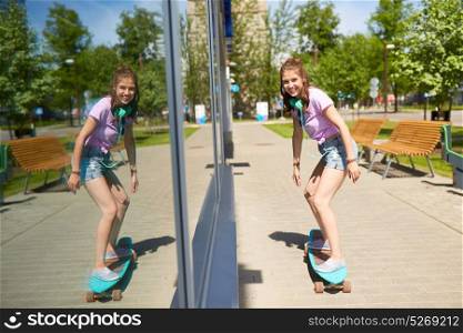 lifestyle, longboarding and people concept - smiling young woman or teenage girl with headphones riding on longboard along summer city street. happy teenage girl riding on longboard in summer