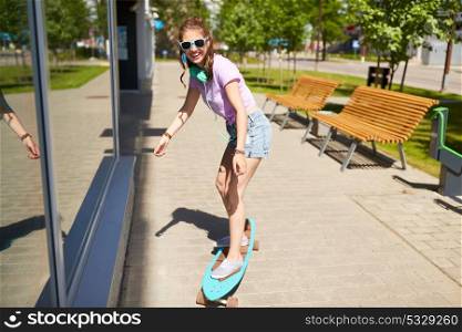 lifestyle, longboarding and people concept - smiling young woman or teenage girl in sunglasses riding on longboard along summer city street. happy teenage girl in shades riding on longboard