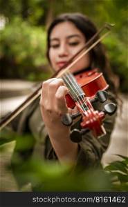 Lifestyle of girl with her violin playing a melody outdoors, Concept of smiling female violinist. Latin girl playing the violin outdoors. Portrait of a latin girl playing the violin outdoors