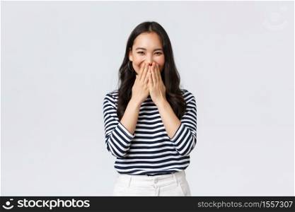 Lifestyle, people emotions and casual concept. Cute silly asian female giggle while gossiping and mocking someone, cover mouth as smiling and laughing carefree.. Lifestyle, people emotions and casual concept. Cute silly asian female giggle while gossiping and mocking someone, cover mouth as smiling and laughing carefree
