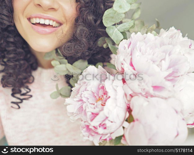 Lifestyle photo of beautiful smiling woman with pink peonies. Bouquet as gift. Emotions of happiness and joy
