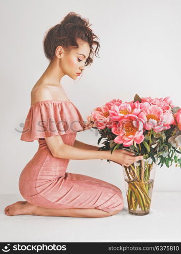 Lifestyle photo of beautiful young woman with pink peonies. Bouquet as gift. Emotions of happiness and joy. Valentines day. Mothers day