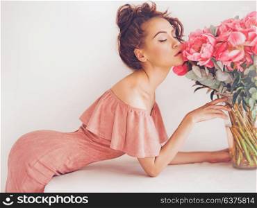 Lifestyle photo of beautiful young woman with pink peonies. Bouquet as gift. Emotions of happiness and joy. Valentines day. Mothers day
