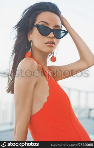Lifestyle portrait of beautiful pregnant woman in red swimsuit in swimming pool. Beautiful pregnancy. Beauty and health