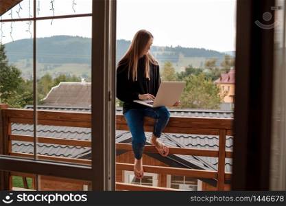 lifestyle portrait of pretty young girl working at the laptop in the balcony of hotel in mountains. Freelance. Dream work.. lifestyle portrait of pretty young girl working at the laptop in the balcony of hotel in mountains. Freelance. Dream work