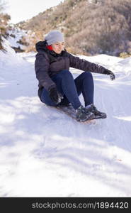 Lifestyle portrait of pretty young woman sliding down hill on snow saucer sled outdoors in winter. Funny face. Emotional photo. Winter sports with snow. Sledding - fun in the mountains. Winter fun
