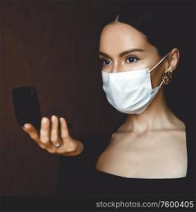 Lifestyle portrait of young beautiful lady in medical mask looking in a compact mirror. Stay home. Coronavirus. Quarantine. Coronavirus pandemic in the world