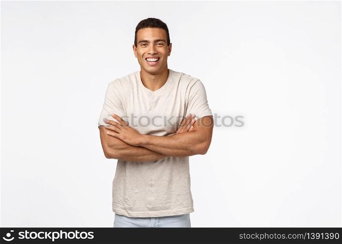 Lifestyle, sport and people concept. Handsome happy young hispanic guy in casual t-shirt, cross arms over chest, showing strong muscles, laughing and smiling carefree, enjoy funny conversation.. Lifestyle, sport and people concept. Handsome happy young hispanic guy in casual t-shirt, cross arms over chest, showing strong muscles, laughing and smiling carefree, enjoy funny conversation