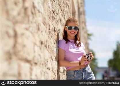 lifestyle, summer and people concept - smiling young woman or teenage girl in sunglasses with camera on city street. happy teenage girl in shades with camera on street