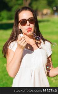 lifestyle, summer vacation, fun, leisure and people concept - smiling young girl with soap bubbles in park
