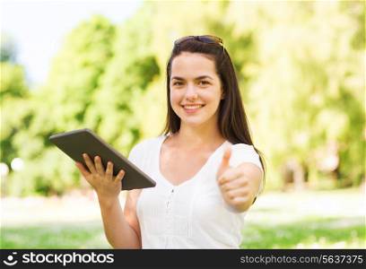 lifestyle, summer vacation, gesture, technology and people concept - smiling young girl with tablet pc showing thumbs up and sitting in park