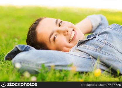 lifestyle, summer vacation, leisure and people concept - smiling young girl lying on grass