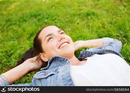lifestyle, summer vacation, leisure and people concept - smiling young girl lying on grass