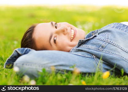 lifestyle, summer vacation, leisure and people concept - smiling young girl lying on grass