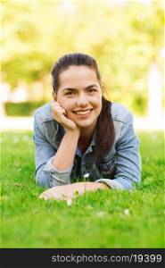 lifestyle, summer vacation, leisure and people concept - smiling young girl lying on grass in park