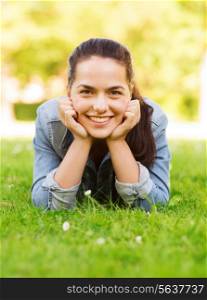 lifestyle, summer vacation, leisure and people concept - smiling young girl lying on grass in park