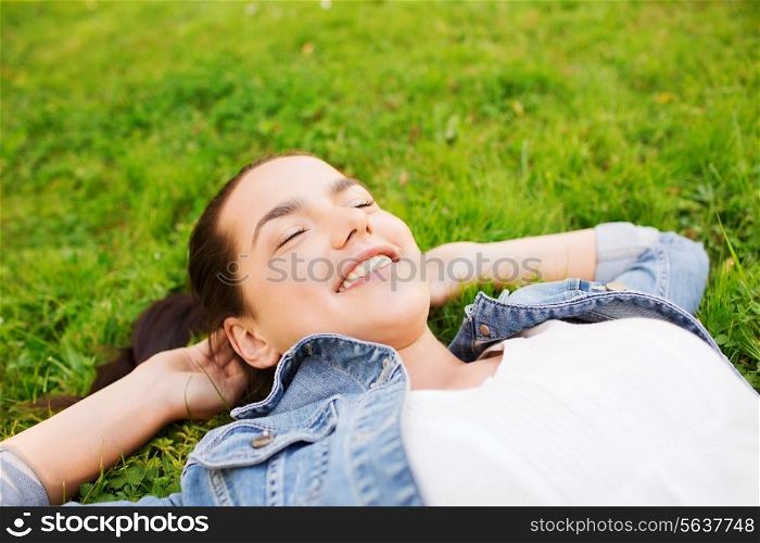 lifestyle, summer vacation, leisure and people concept - smiling young girl with closed eyes lying on grass