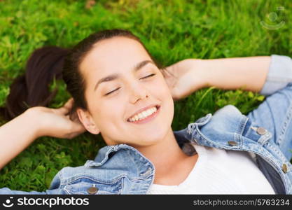 lifestyle, summer vacation, leisure and people concept - smiling young girl with closed eyes lying on grass