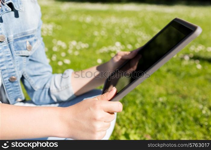 lifestyle, summer, vacation, technology and people concept - close up of young girl with tablet pc sitting on grass in park