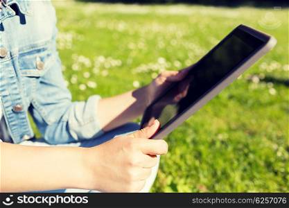 lifestyle, summer, vacation, technology and people concept - close up of young girl with tablet pc sitting on grass in park