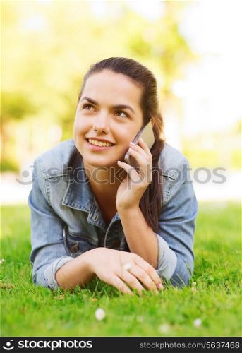 lifestyle, summer vacation, technology, leisure and people concept - smiling young girl with smartphone talking and lying on grass in park