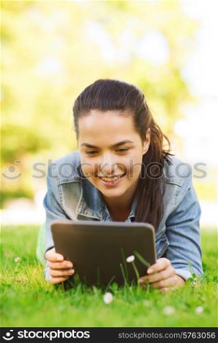 lifestyle, summer vacation, technology, leisure and people concept - smiling young girl with tablet pc computer lying on grass in park