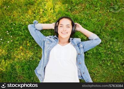 lifestyle, summer vacation, technology, music, leisure and people concept - smiling young girl in headphones lying with closed eyes on grass