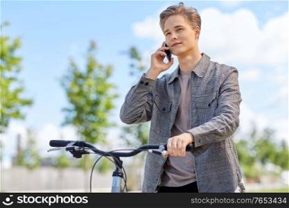 lifestyle, transport and people concept - young man or teenage boy with bicycle calling on smartphone in city. young man with bicycle calling on phone in city