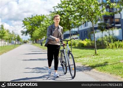 lifestyle, transport and people concept - young man or teenage boy with bicycle walking along city street. young man with bicycle walking along city street