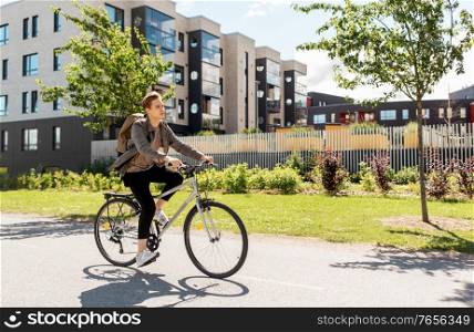 lifestyle, transport and people concept - young man or teenage student boy with backpack riding bicycle on city street. young man riding bicycle on city street