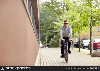 lifestyle, transport and people concept - young man riding bicycle on city street