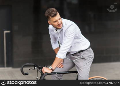 lifestyle, transport and people concept - young man with bicycle and headphones on city street