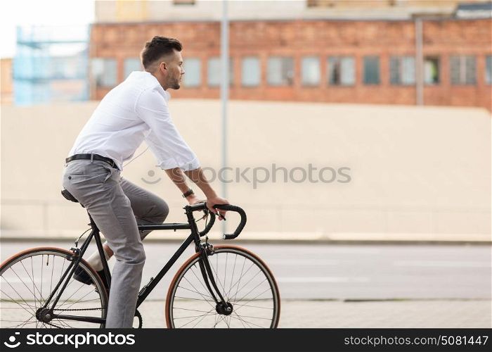 lifestyle, transport and people concept - young man with headphones riding bicycle on city street. man with headphones riding bicycle on city street