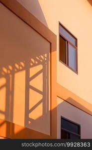 Light and shadow of metal warehouse column on orange concrete wall surface of industrial office building in vertical frame, perspective side view and minimal style