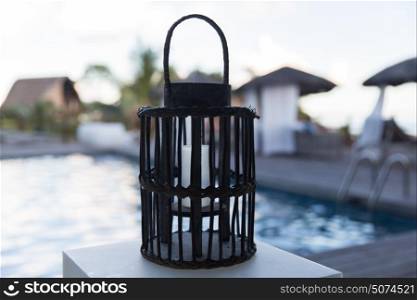light and summer holidays concept - lantern with extinct candle at outdoor swimming pool. lantern with candle at outdoor swimming pool