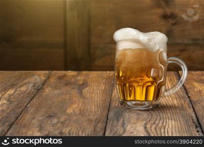 Light beer in mug on wooden background