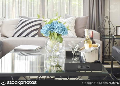 Light blue flower with wine bottles and glasses of wine on the tabla in modern living room