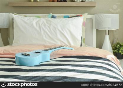 Light blue ukulele on striped bedding