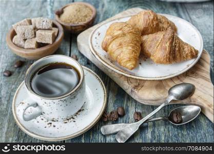 Light breakfast consisting of a cup of black coffee and croissants