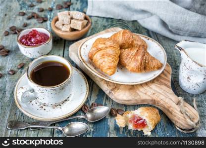 Light breakfast consisting of a cup of black coffee and croissants with a stuffing from raspberry jam